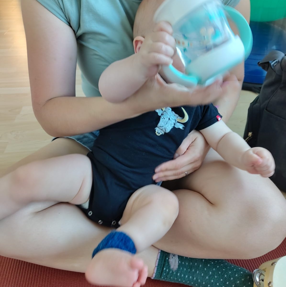 Baby mit Trinkflasche auf dem Schoss